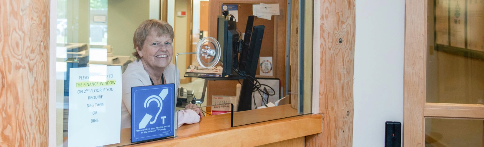 County staff member standing at a customer service counter.